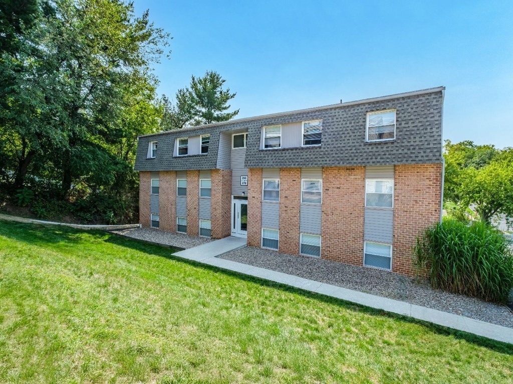 A modern brick house with a sloped roof and a well-maintained lawn in front.