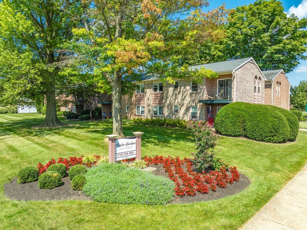 A well-maintained garden with a sign that reads "Millbrook Estates" in front of a building.