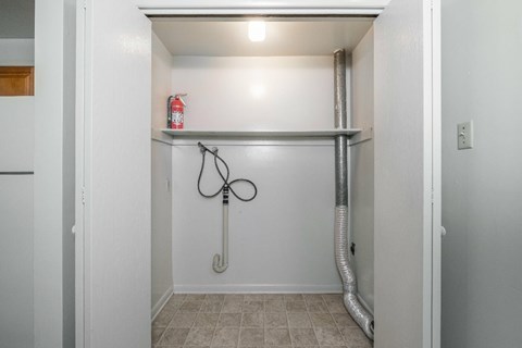 A white hallway with a fire extinguisher on the shelf.