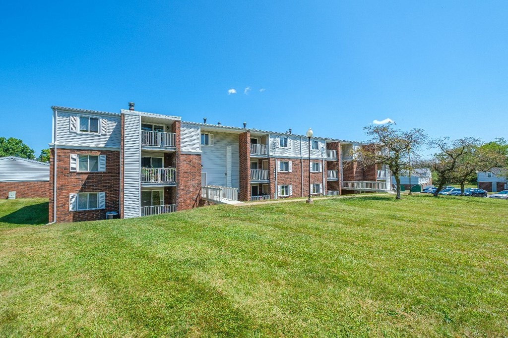 A row of red brick apartment buildings with green grass in front.