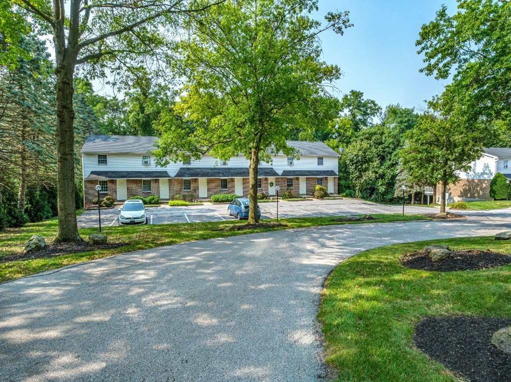 A white house with a driveway and trees in front.