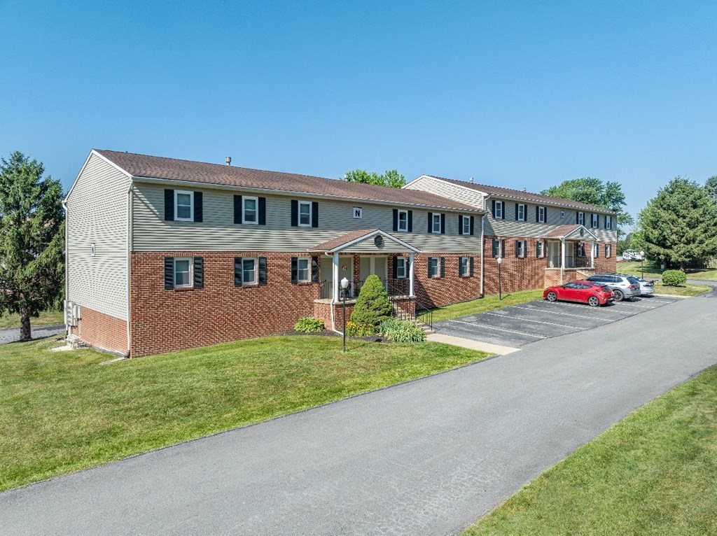 A red car is parked in front of a brick building.