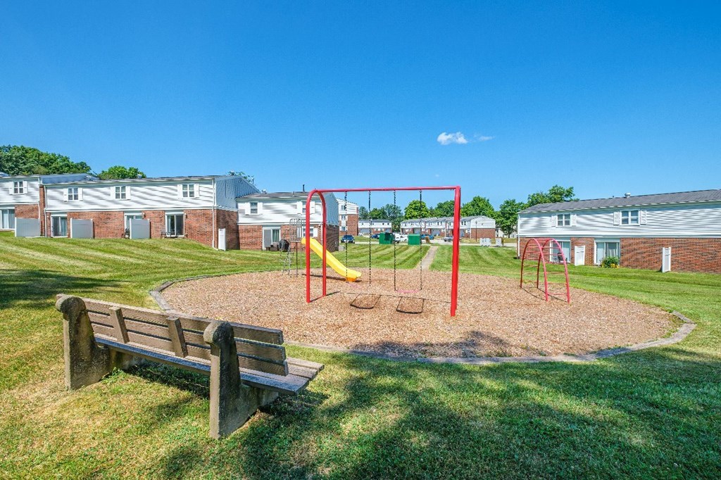 A playground with a swing set and a bench in the foreground.