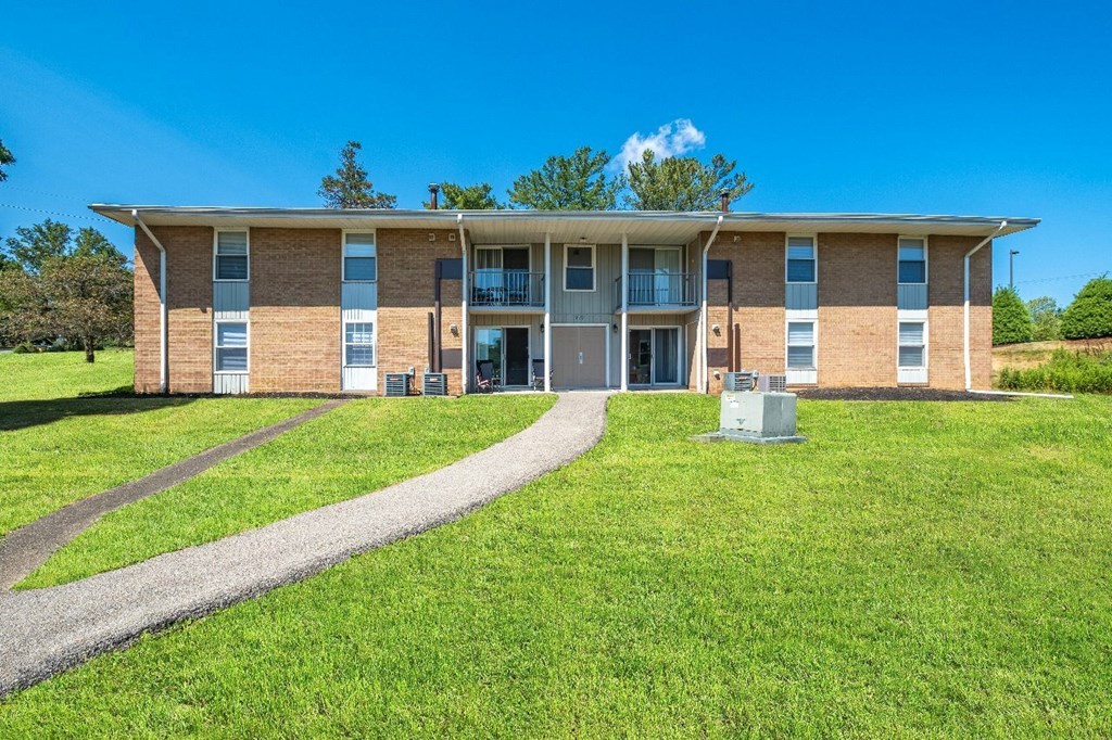 A large brick building with a green lawn in front.