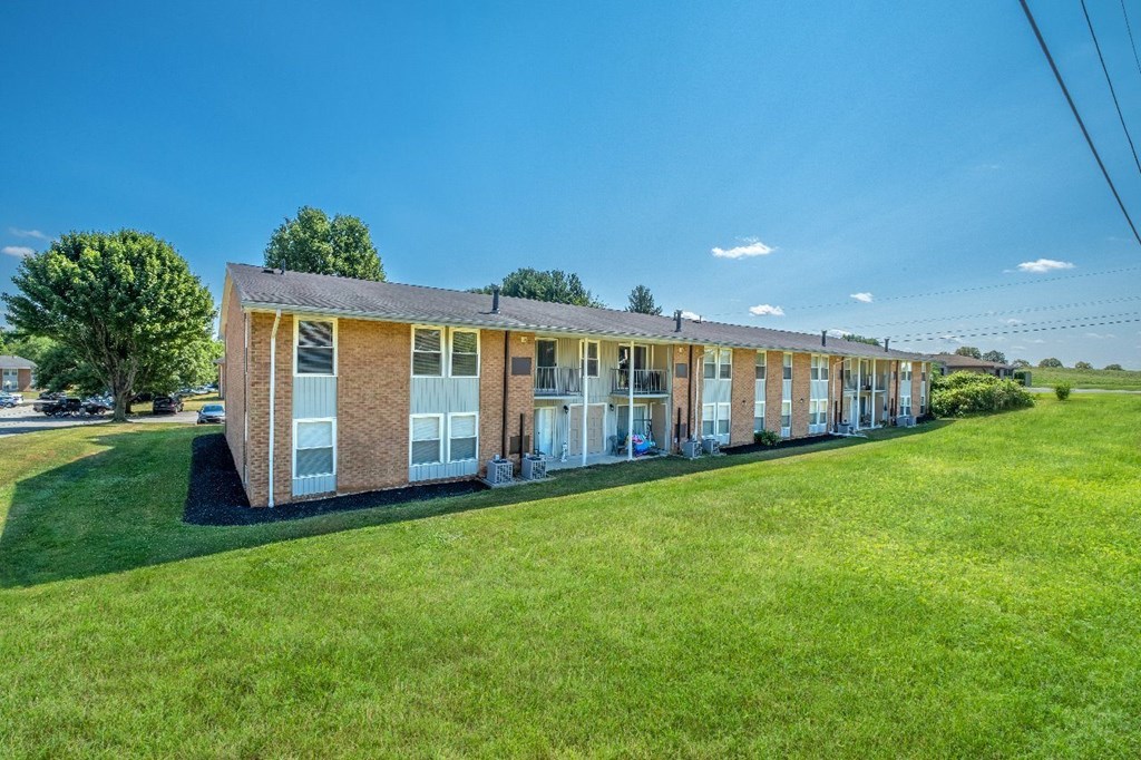 A long building with a green lawn in front.
