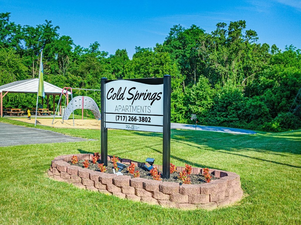 A sign for Cold Springs Apartments is surrounded by a flower bed.