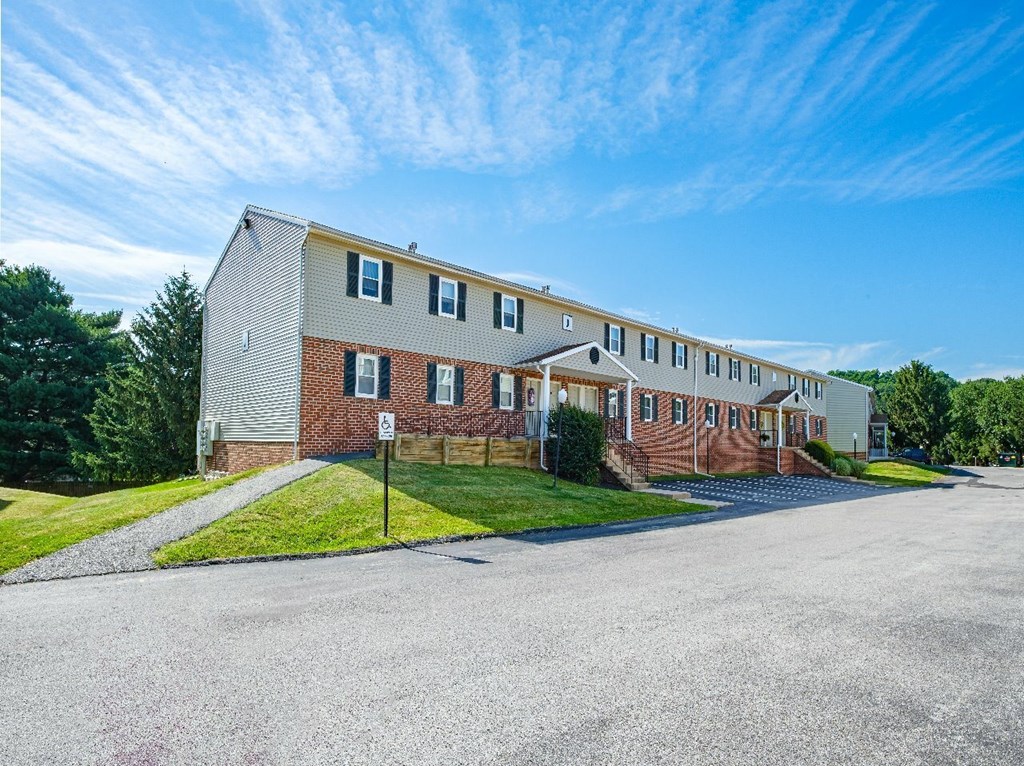 A long building with a grey roof and a red brick wall.