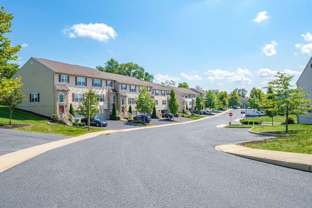 A street view of a residential area with apartment buildings on the left and a stop sign on the right.