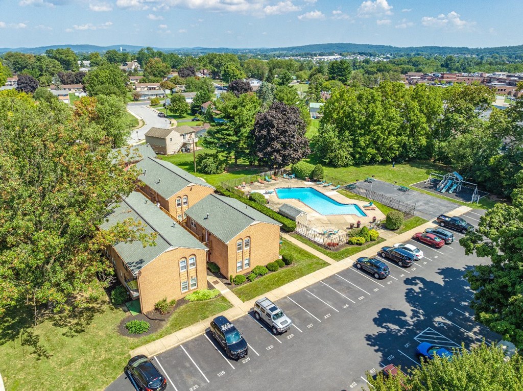 A parking lot with cars and a building with a pool in the background.