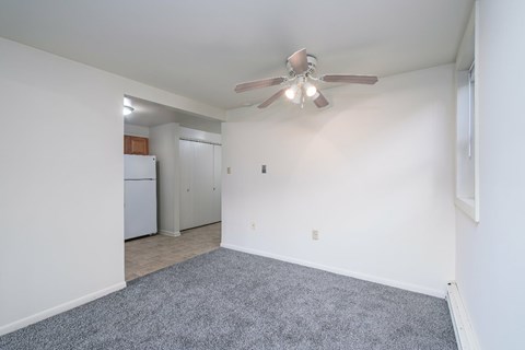 A room with a ceiling fan and a grey carpet.