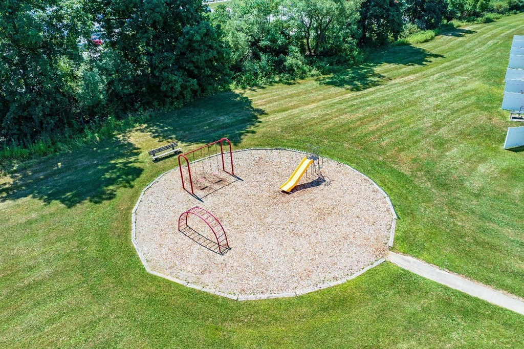 A playground with a yellow slide and red monkey bars.