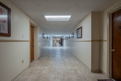 A long hallway with doors on both sides and pictures on the wall.