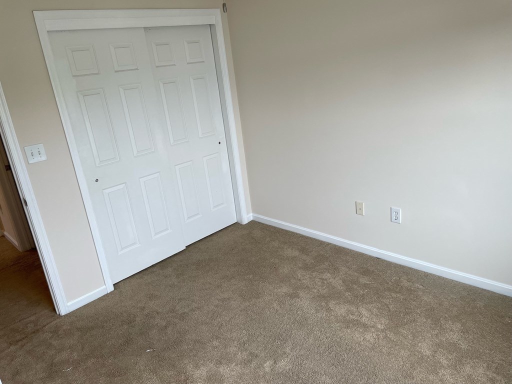 A white door is in a room with carpeted floor.