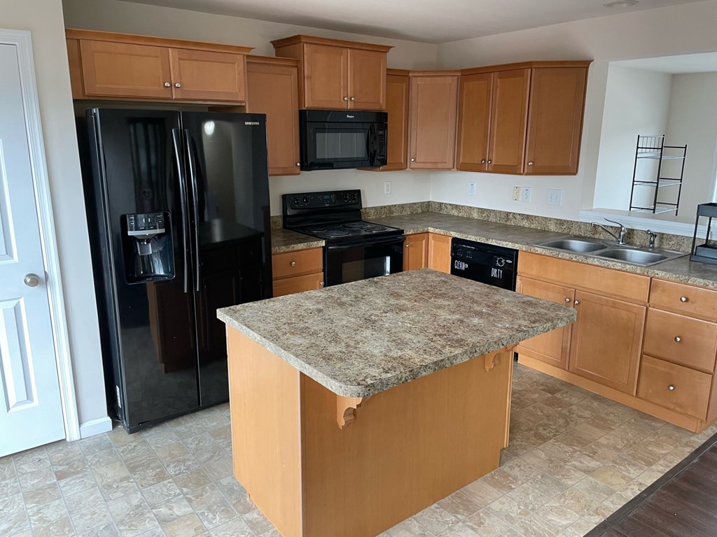 A kitchen with a granite countertop and wooden cabinets.