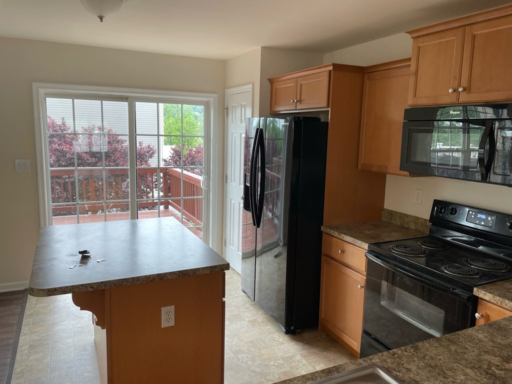 A kitchen with a black refrigerator, stove, and microwave.