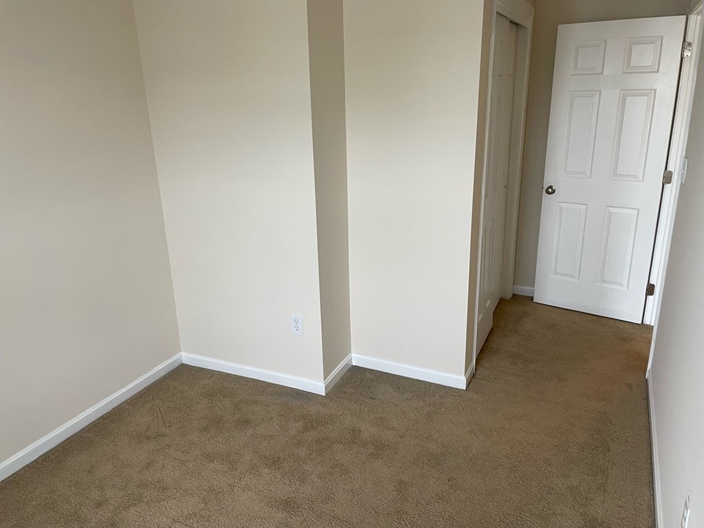 A room with a white door and carpeted floor.