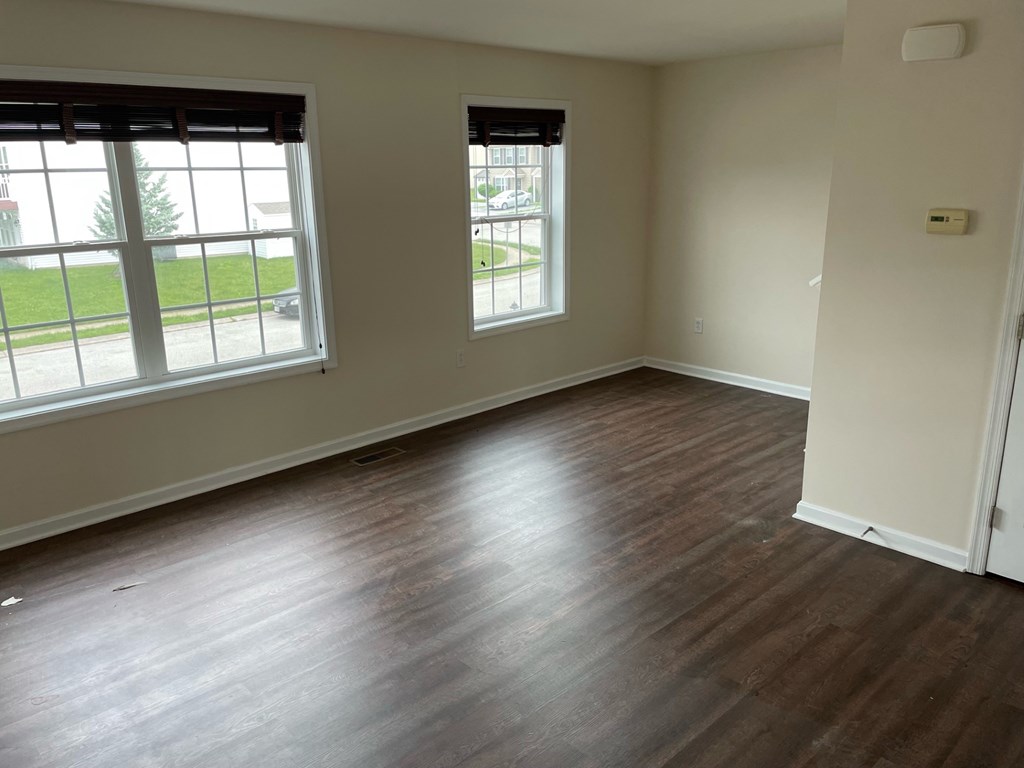 A room with wooden floors and two windows.