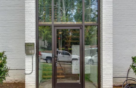 A white building with a brown door and glass window.