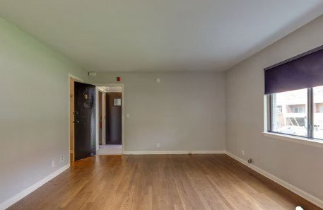 A room with wooden floors and a window with blinds.