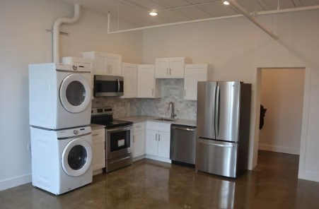 A kitchen with a refrigerator, oven, microwave, and washing machine.