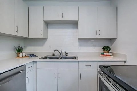 A kitchen with white cabinets and a stainless steel sink.