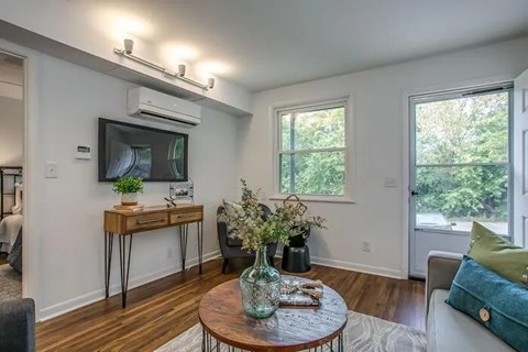 A living room with a brown table and a television on the wall.