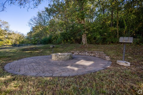 A circular brick patio with a stone fireplace in the middle.