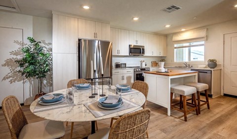 A modern kitchen with a dining table set for two.