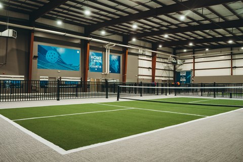 A tennis court inside a building with a sign that says "Home Court".