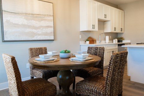 A dining room with a table set for two and a painting on the wall.