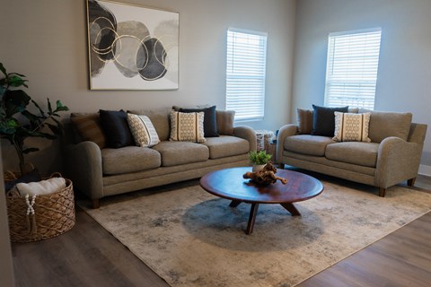 A living room with a large couch, a coffee table, and a painting on the wall.