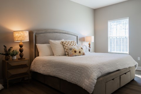 A bedroom with a large bed and a nightstand with a lamp.