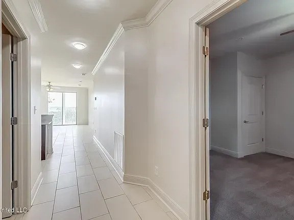 A long white hallway with a door on the right.
