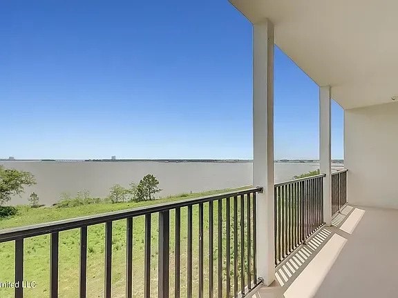 A balcony with a view of a body of water and trees.
