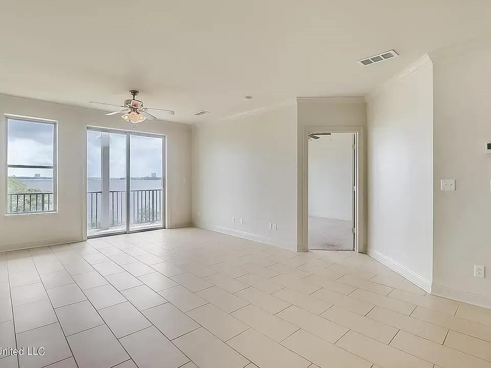 A spacious room with a ceiling fan and sliding glass doors leading to a balcony.