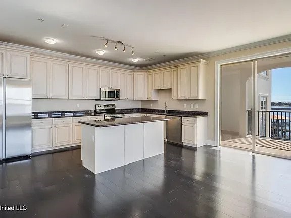 A kitchen with white cabinets and black countertops.
