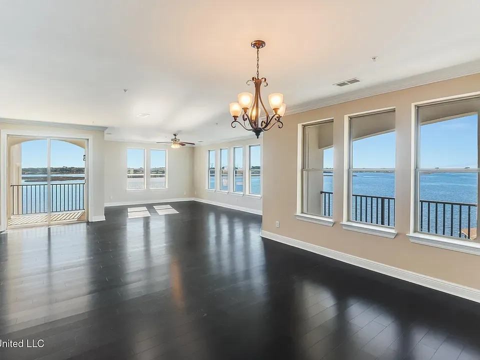 A large empty room with a chandelier and a view of the water.