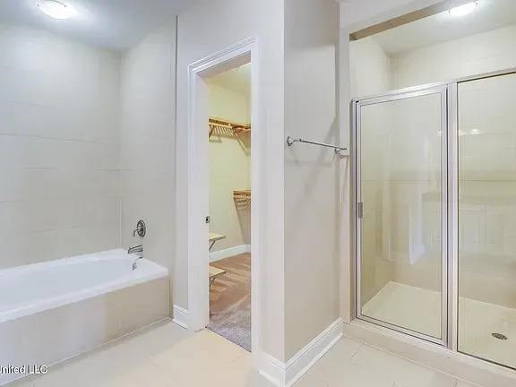 A white bathroom with a glass shower door and a bathtub.