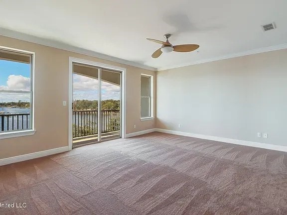 A room with a ceiling fan and sliding glass doors.