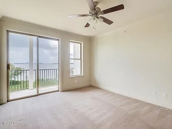 A room with a ceiling fan and sliding glass doors.
