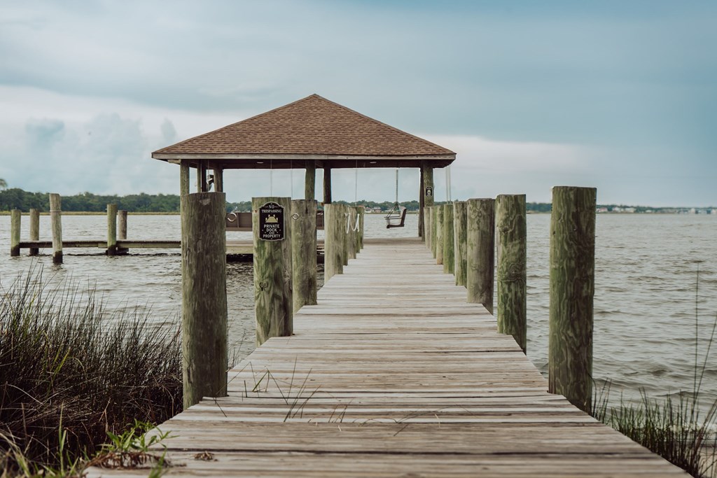 A wooden pier leads to a gazebo in the middle of a body of water.