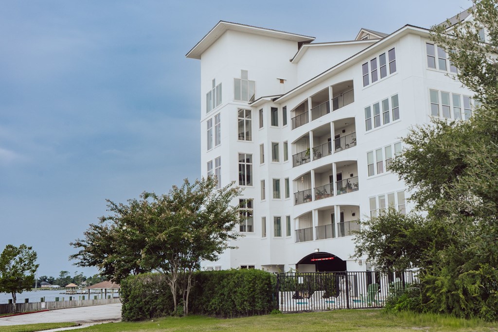 A white building with balconies and a black gate in front.