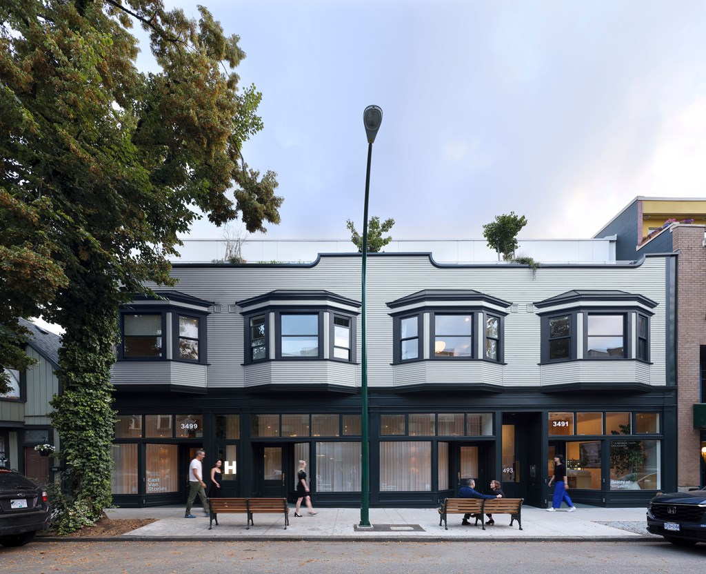 A street view of a building with people walking on the sidewalk.