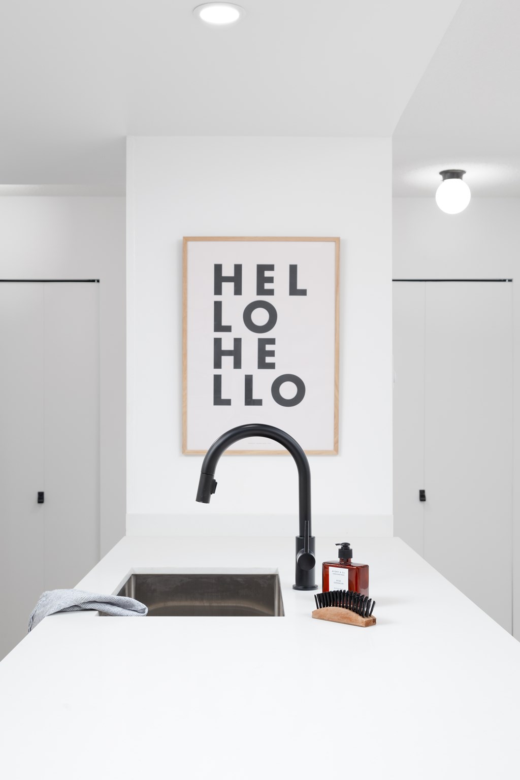 A bathroom with a sink and a poster that says "HELLO".