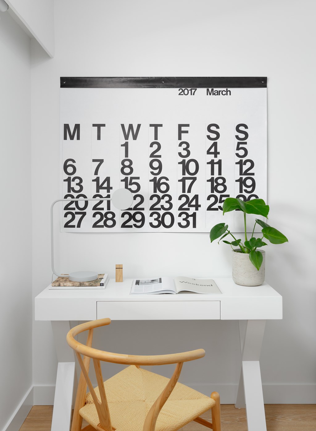 A calendar for March 2017 is on the wall above a desk with a chair.