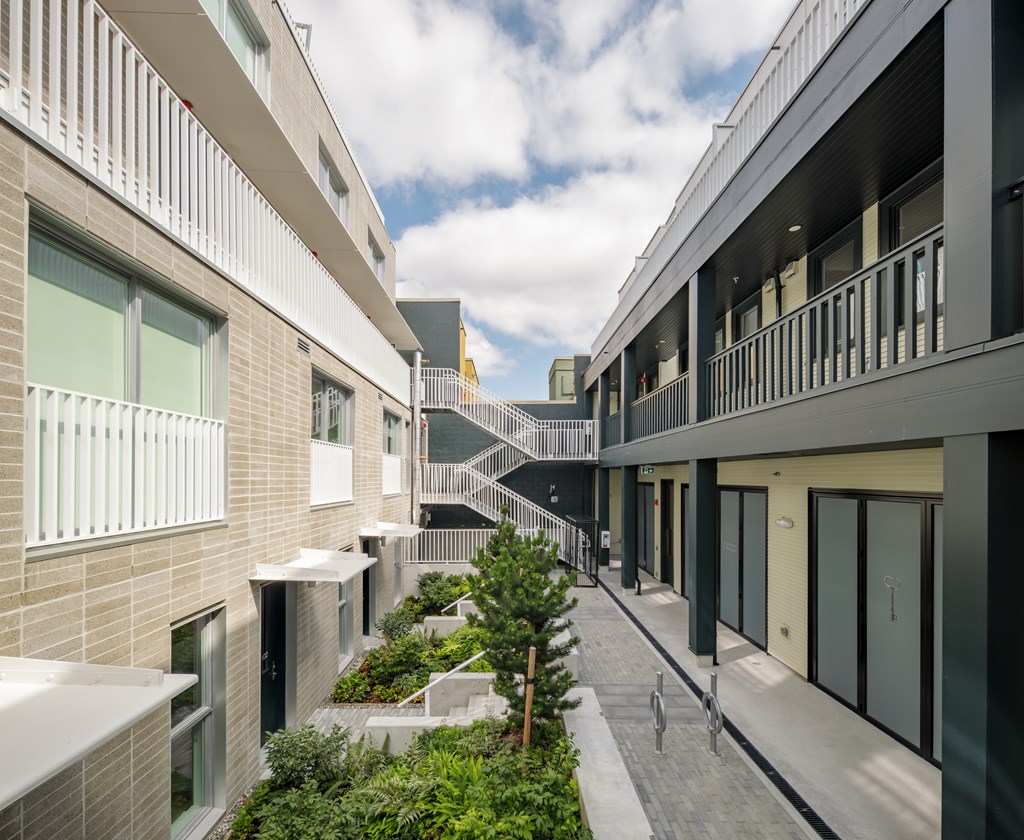 A modern building with a balcony and a tree in front.