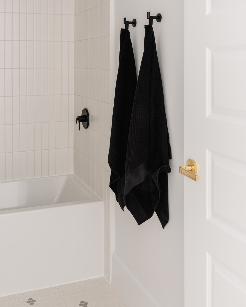 Two black towels hanging on a towel rack.