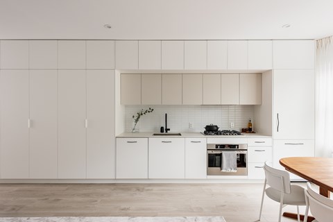 A modern kitchen with white cabinets and a wooden table.