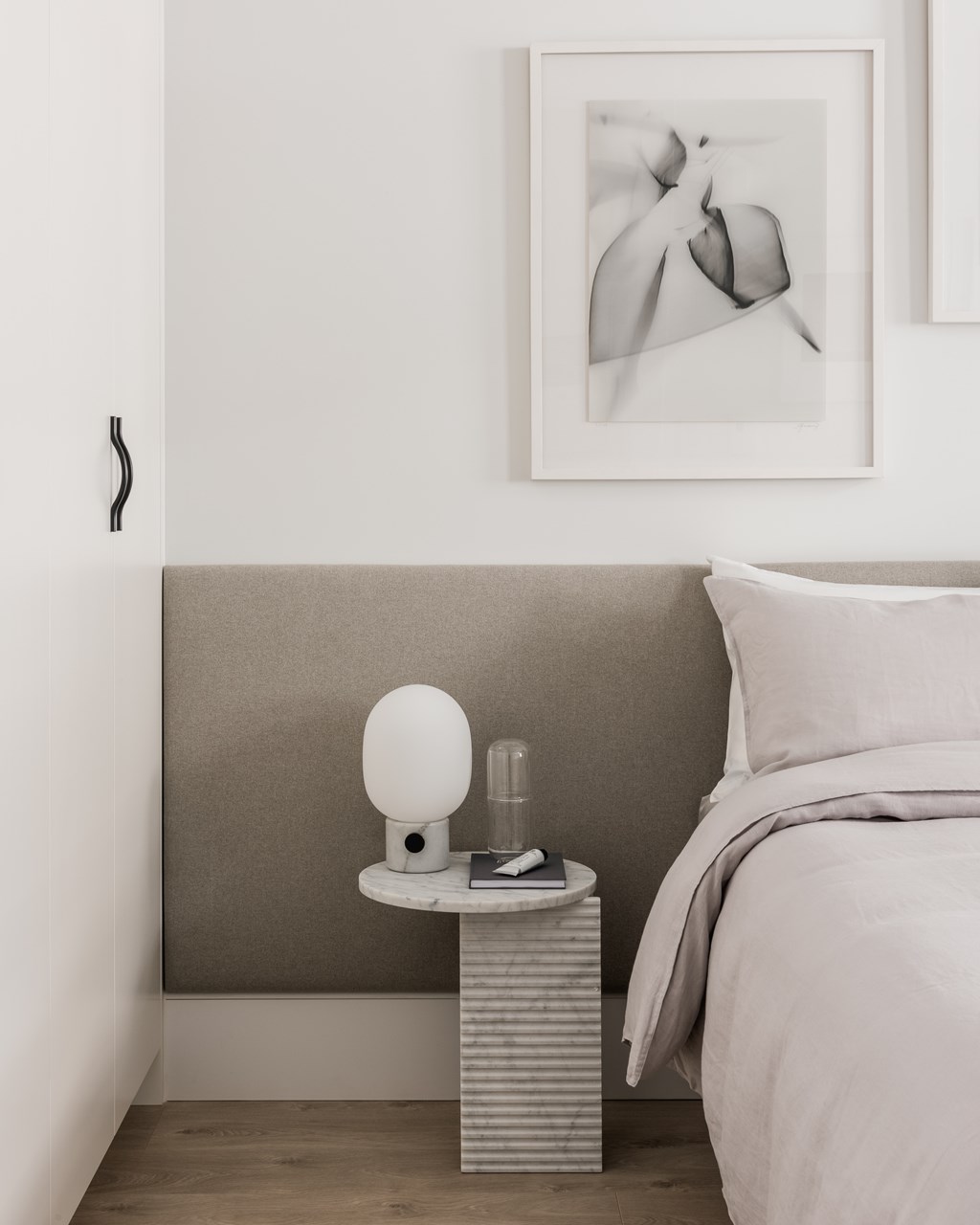 A bedroom with a bed, nightstand, and a picture on the wall.