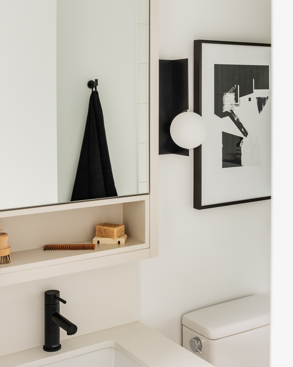 A black umbrella is hanging on a hook on a white wall.